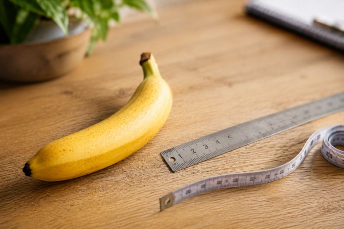 Iki kiek metų auga varpa, bananas šalia metalinės liniuotės ir matavimo juostos ant medinio stalo